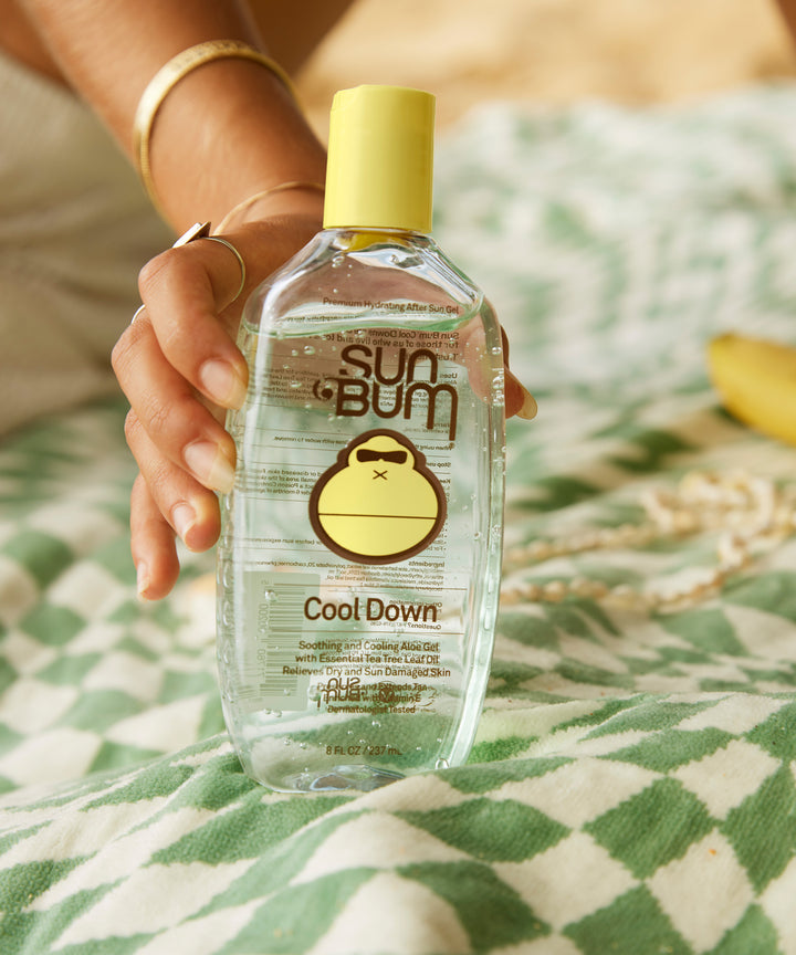 Bottle of Sun Bum After Sun Cool Down Gel with soothing Aloe, placed on a patterned cloth, Sun Bum