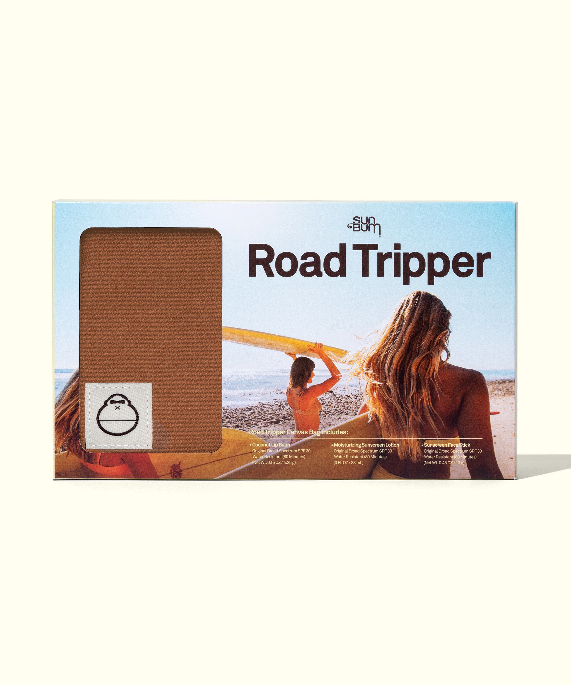 Road Tripper travel kit shown in light blue packaging, featuring beachy scene with surfers at sunset. Product window displays brown fabric pouch perfect for carrying beach essentials. By Sun Bum.