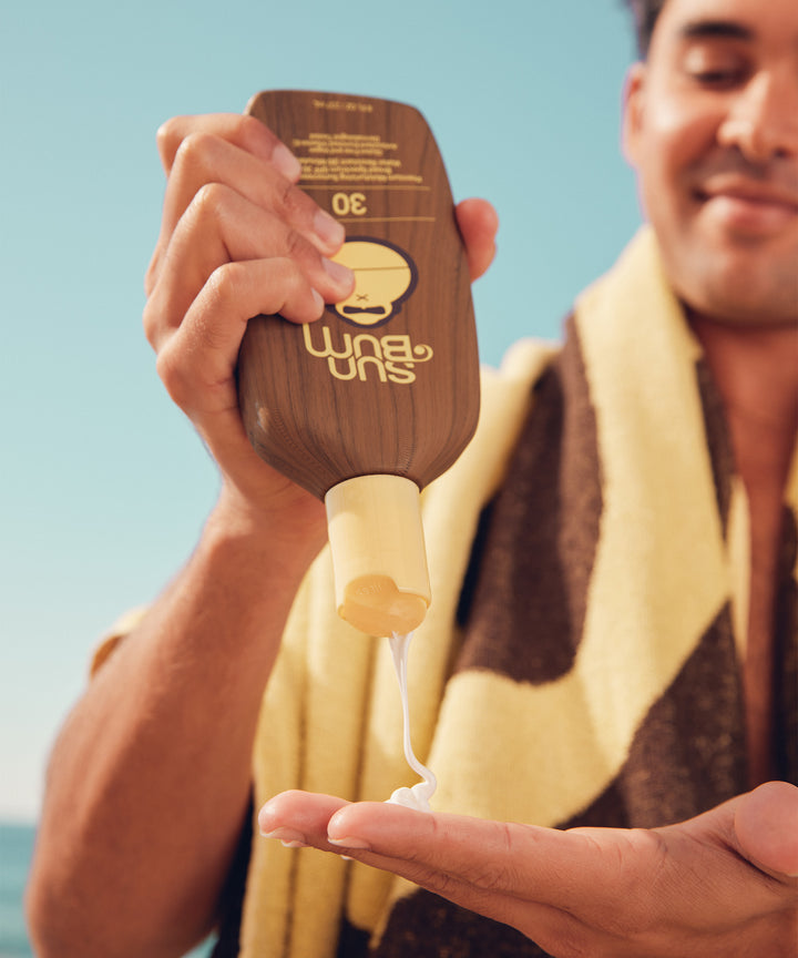 Man applying Original SPF 30 Sunscreen Lotion on the beach, Sun Bum