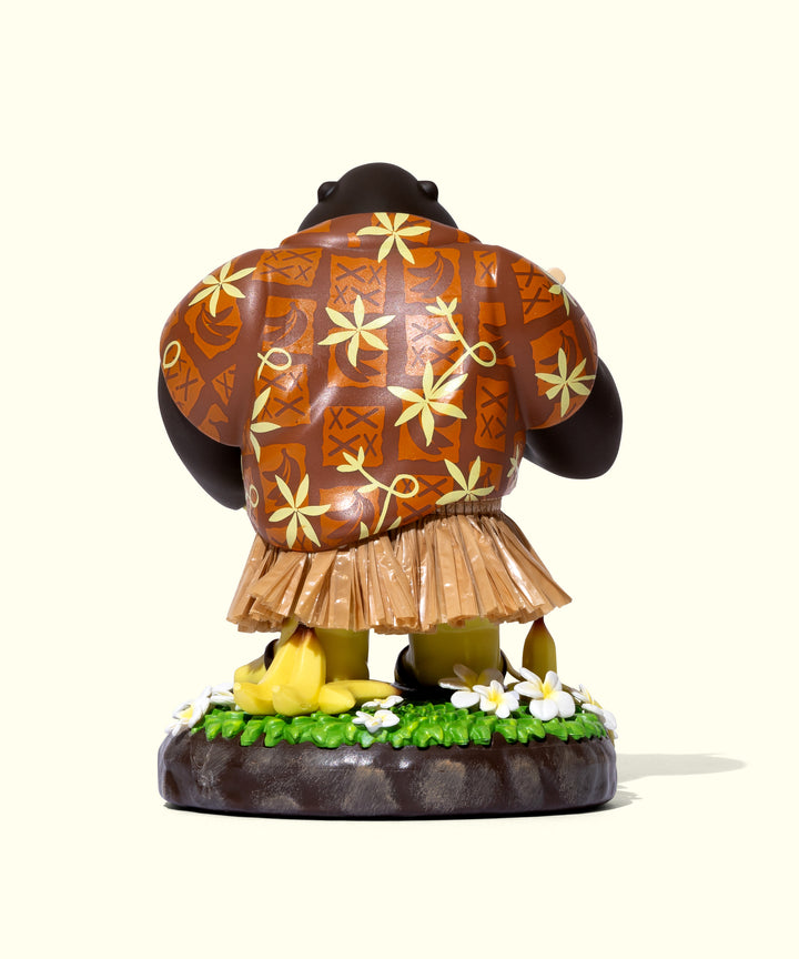 Back view of Hula Sonny figurine wearing a floral-patterned shirt and grass skirt, surrounded by tropical flowers. Sun Bum