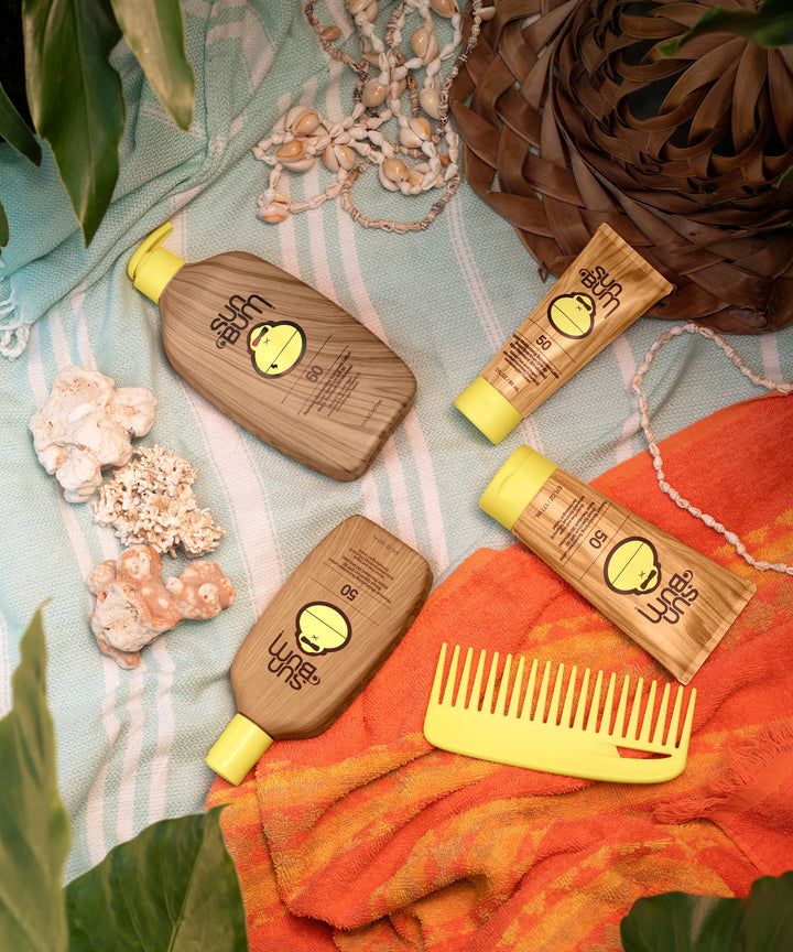 Original SPF 50 Sunscreen Lotion by Sun Bum laid out on a beach towel with seashells and a yellow comb.